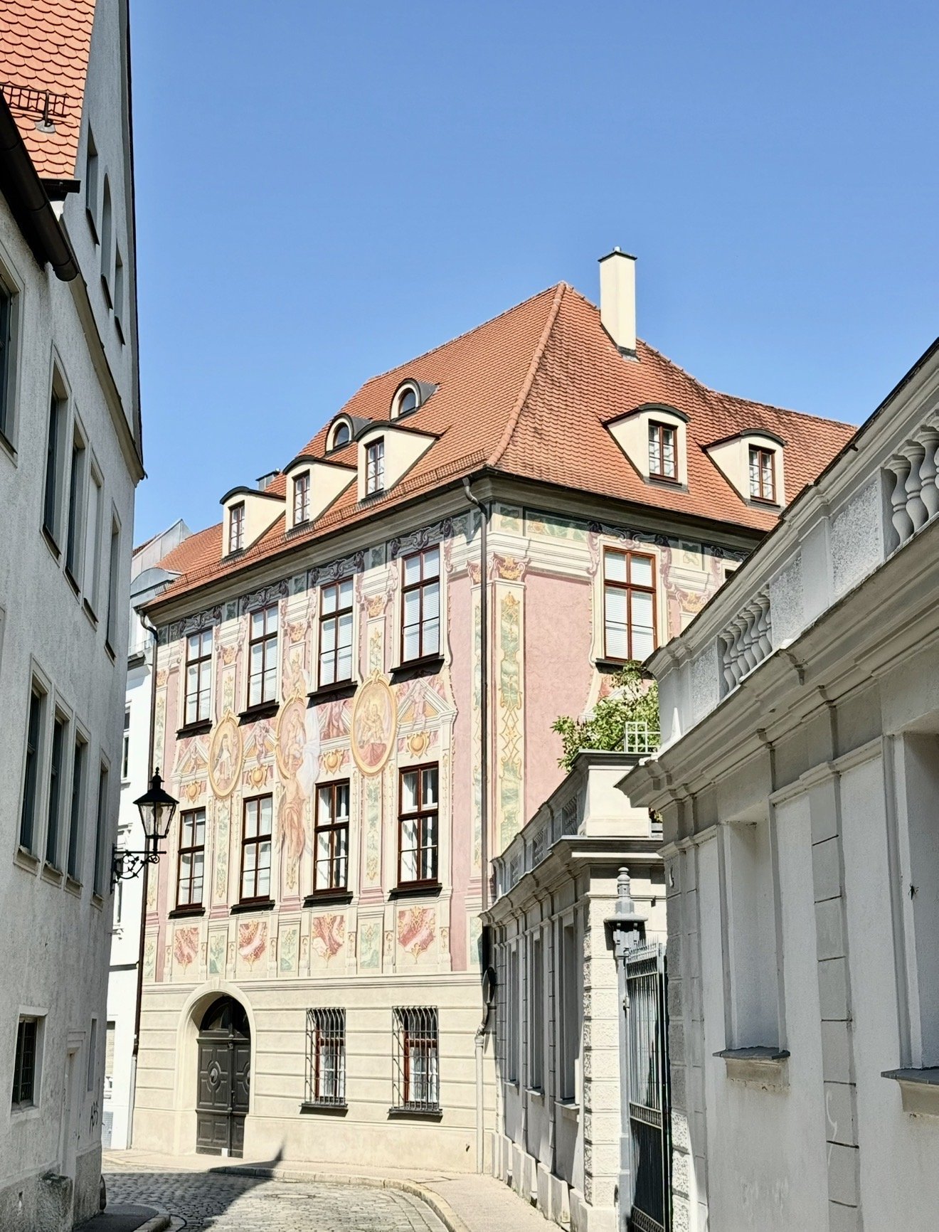 Historische Fassade mit Freskenmalerei in einer Augsburger Gasse im Sonnenlicht